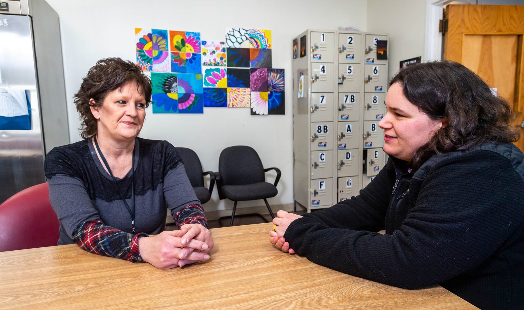 A woman talks to another woman at a table.