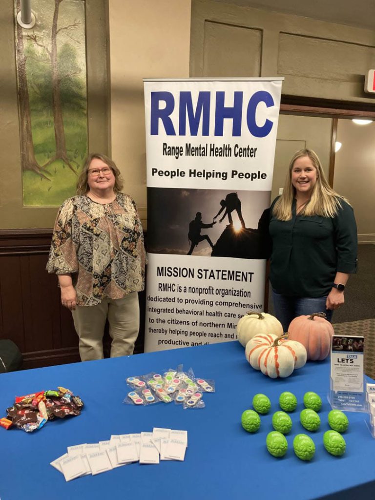 Two women stand beside an RMHC banner at a tabling event.