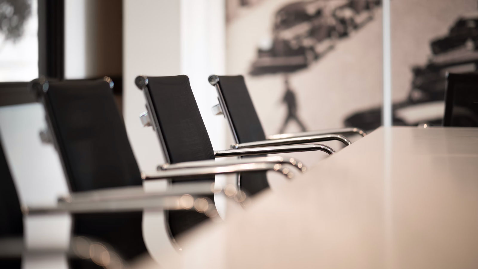 A row of black chairs face a conference room table.